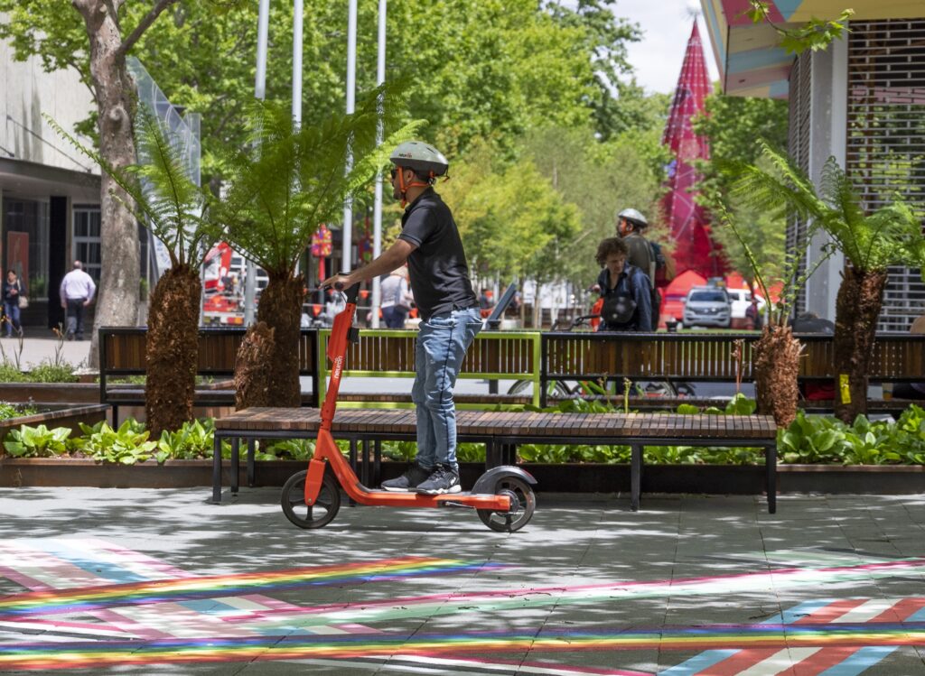 Student riding an e-scooter at Garema Place in Canberra City